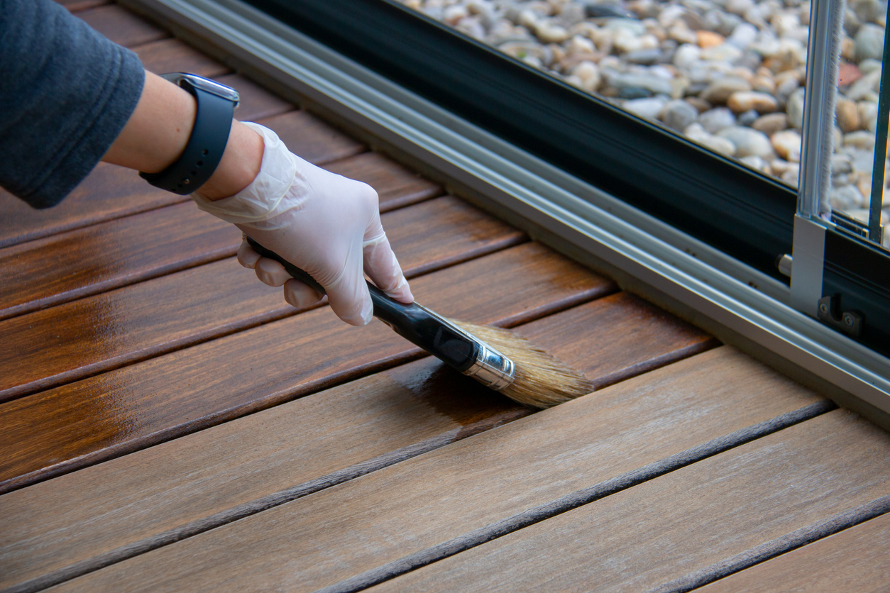 Deck staining, worker hand applying deck oil
